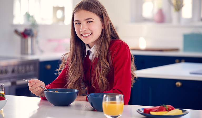 portrait of smiling teenage girl wearing school uniform in kitch